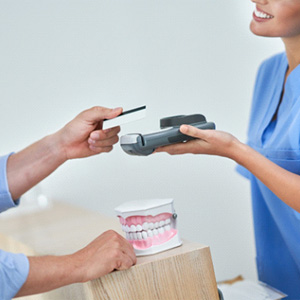 Male patient handing over card to pay for orthodontic treatment