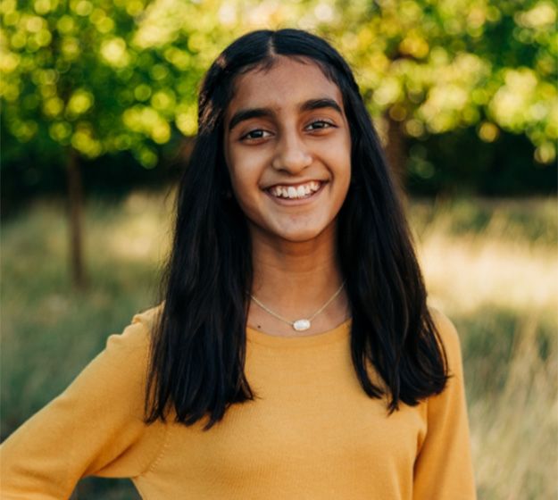 A young girl outside on the beach and smiling after receiving her braces in Plano