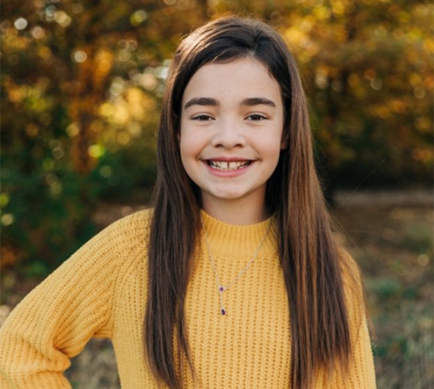 Young girl holding Invisalign in Plano