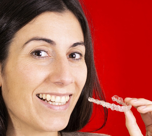 Woman holding Invisalign with red background