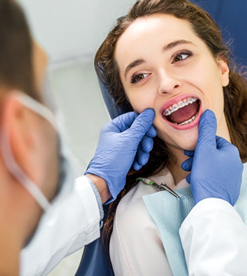 An orthodontist examining a patient’s smile during a follow-up appointment
