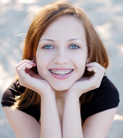 A young girl outside on the beach and smiling after receiving her braces in Plano