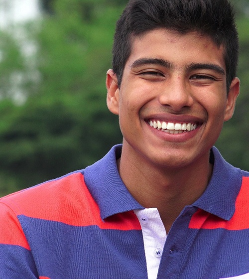 A teenage boy smiling after having his teeth aligned with braces