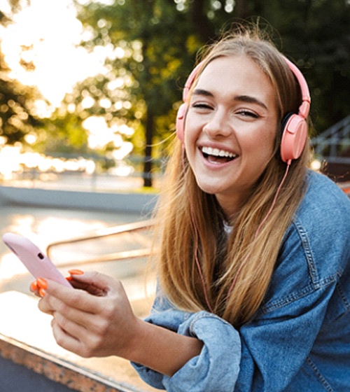 Teenage girl with headphones smiling after braces in Plano, TX