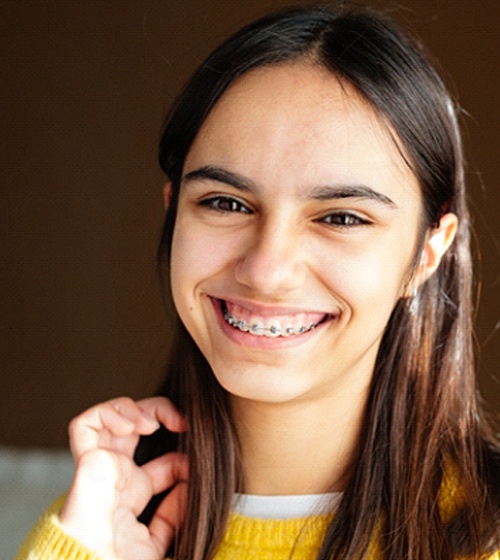A female teenager smiles and exposes her metal braces
