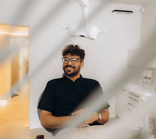 Patient with black glasses smiling in treatment chair