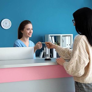 Woman in dental office, using card to pay for treatment