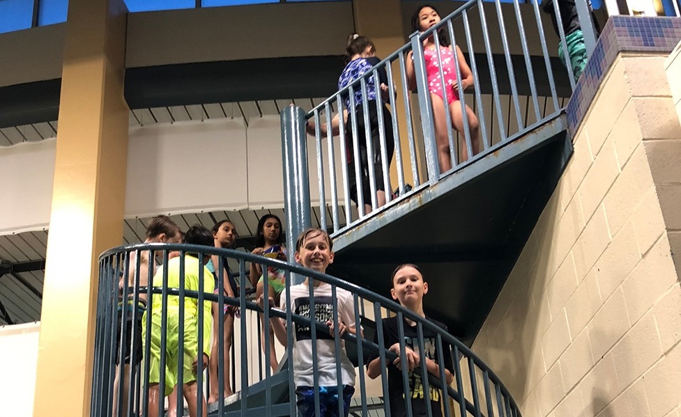 Kids walking up stairs at community pool party event