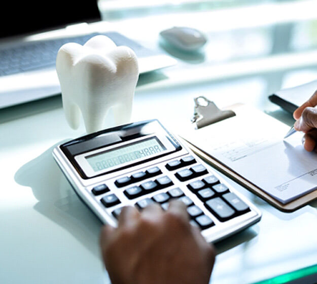 someone using calculator and roms on a desk with a large model tooth and a laptop
