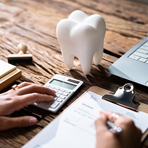 Hands using calculator to budget for dental care