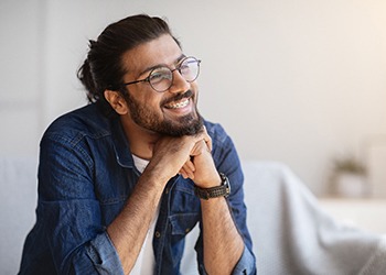 smiling person resting their chin on their hands and staring out a window