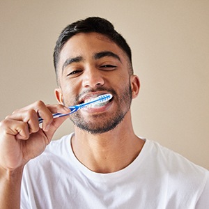 Man smiling while brushing teeth