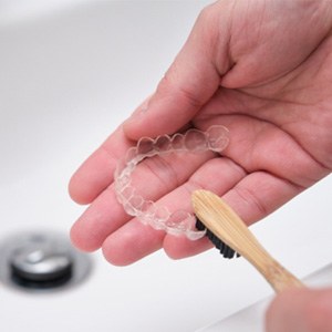 Patient using toothbrush to clean aligner