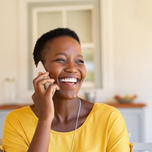 Woman in yellow shirt smiling while talking on phone
