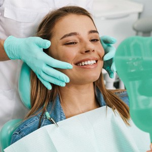 Young woman smiling at reflection in handheld mirror