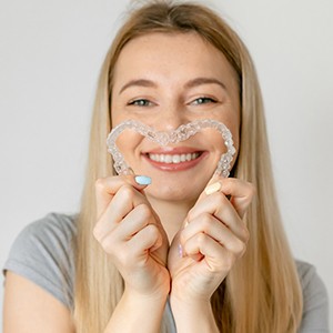 Invisalign patient holding two aligners to form heart shape