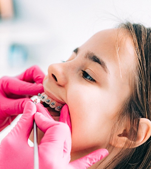 A young female allowing the orthodontist to look inside her mouth to ensure everything looks fine and her braces are intact