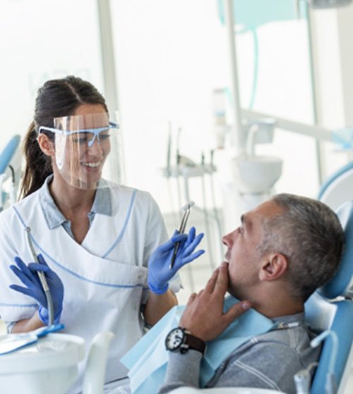 Patient sitting in treatment chair and talking to smiling orthodontist
