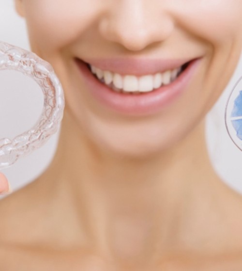 Smiling patient holding up different types of retainers
