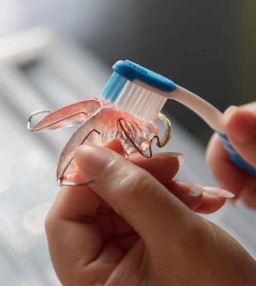 Patient using soft-bristled toothbrush to clean retainer