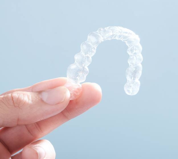 Hand holding Invisalign clear aligner tray