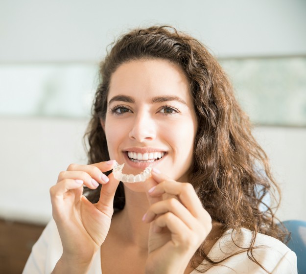 Woman placing adult orthodontics clear alignment tray