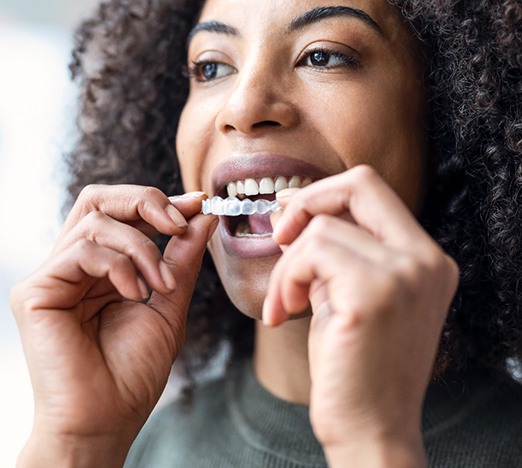 Closeup of patient putting their Invisalign aligners on