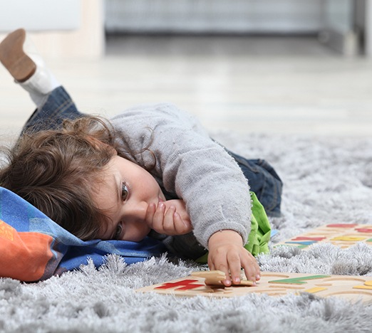 Little girl sucking her thumb while lying on the floor