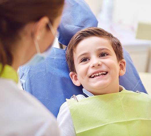 Happy young boy smiling at dental team member