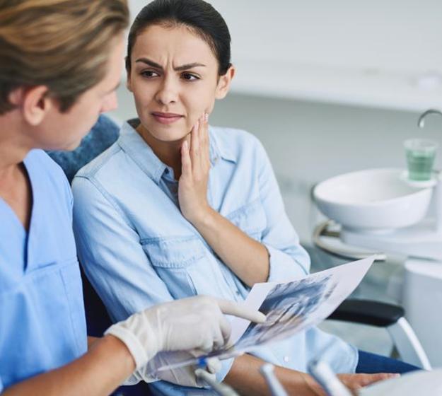 Woman with jaw pain speaking to dental team member