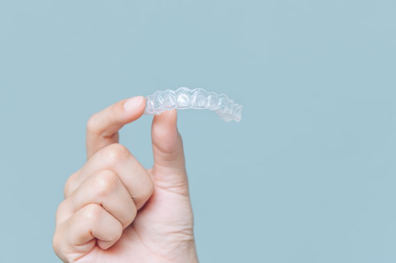 Closeup of patient holding up Invisalign clear braces