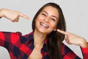 Woman smiling and pointing to her braces