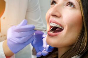 Woman with braces being examined in dentist's chair.